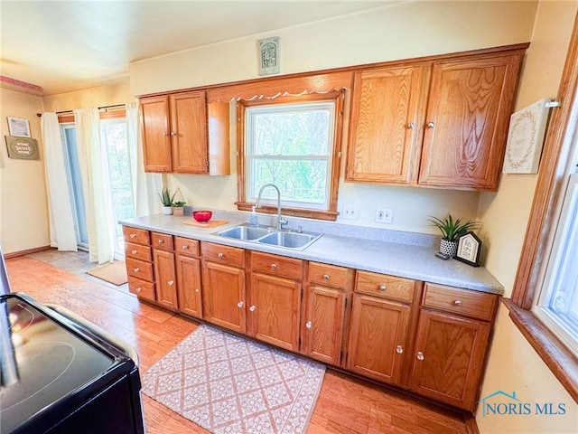 624 Myers St, Toledo, OH 43609 - kitchen with a sink, light wood-style floors, brown cabinetry, and healthy amount of natural light