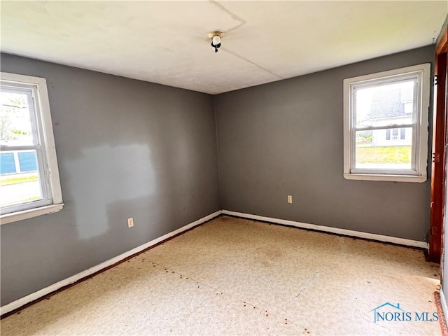 unfurnished room with baseboards
