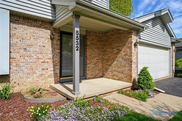 5532 Bentwood Dr, Toledo, OH 43615 - property entrance with brick siding, asphalt driveway, a garage, and a porch