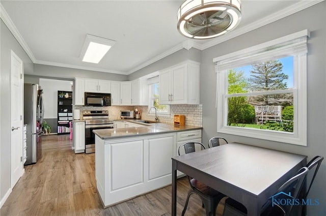 5532 Bentwood Dr, Toledo, OH 43615 - kitchen featuring appliances with stainless steel finishes, a sink, a peninsula, white cabinets, and decorative backsplash