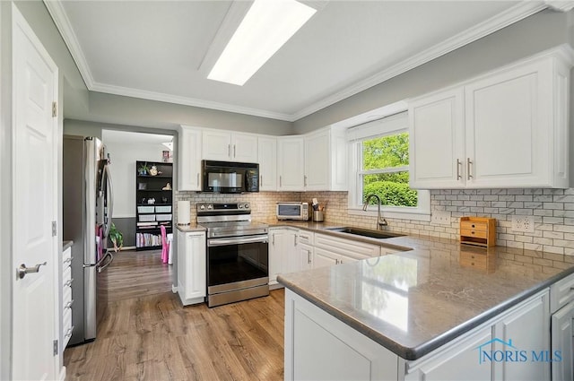 5532 Bentwood Dr, Toledo, OH 43615 - kitchen featuring stainless steel appliances, a sink, light wood-type flooring, white cabinetry, and a peninsula
