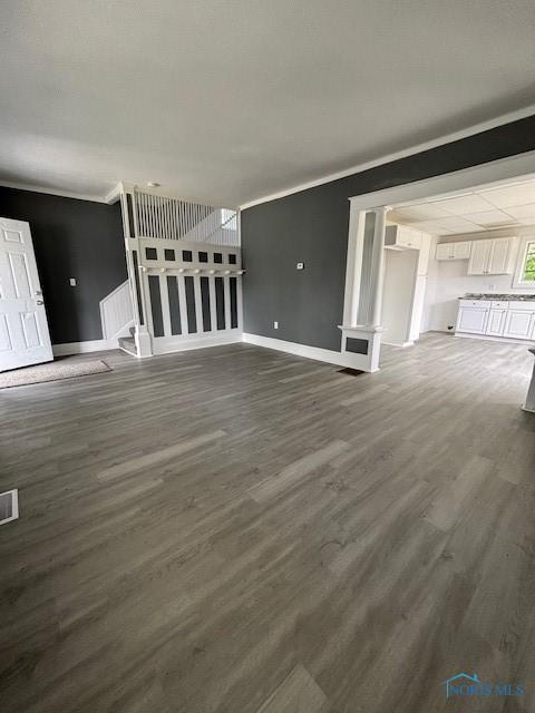 938 Western Ave, Toledo, OH 43609 - unfurnished living room featuring baseboards, dark wood finished floors, and ornamental molding