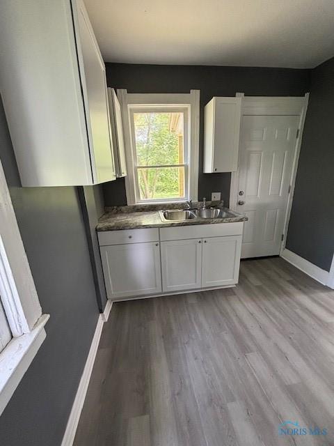 938 Western Ave, Toledo, OH 43609 - kitchen with white cabinetry, baseboards, light wood-style flooring, and a sink