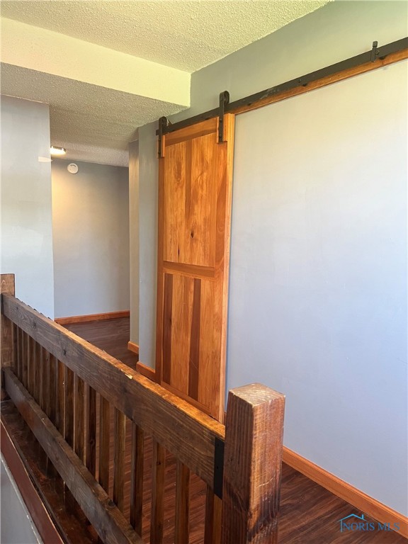 64 Saint Clair St, Tiffin, OH 44883 - staircase featuring a barn door, a textured ceiling, baseboards, and wood finished floors