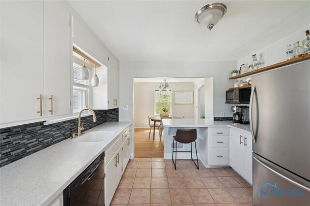 kitchen featuring black appliances, a sink, backsplash, and white cabinets