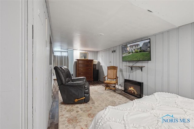 bedroom featuring wood finished floors and a glass covered fireplace