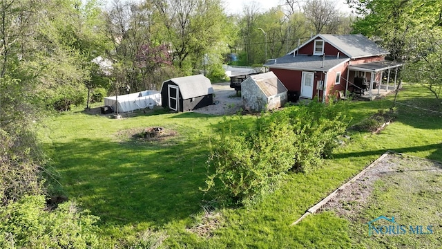 1037 Stevenson St, Napoleon, OH 43545 - view of grassy yard with an outbuilding, a storage shed, and an outdoor fire pit
