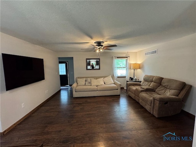 living room with dark wood-type flooring, a ceiling fan, baseboards, and a textured ceiling