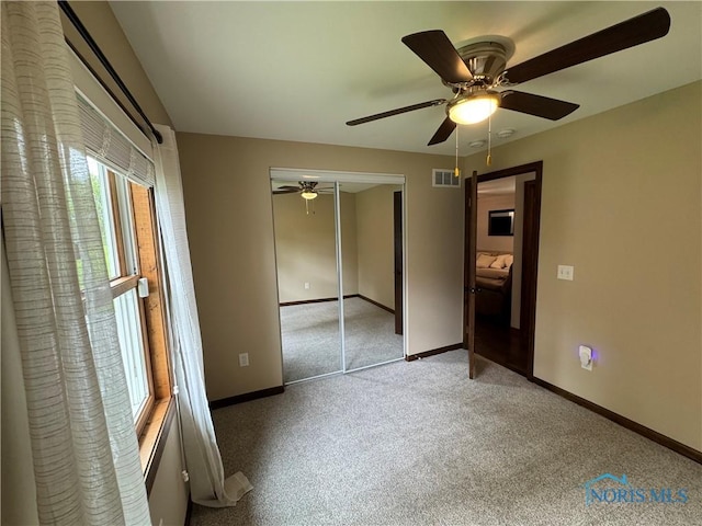 unfurnished bedroom featuring carpet, a closet, baseboards, and a ceiling fan
