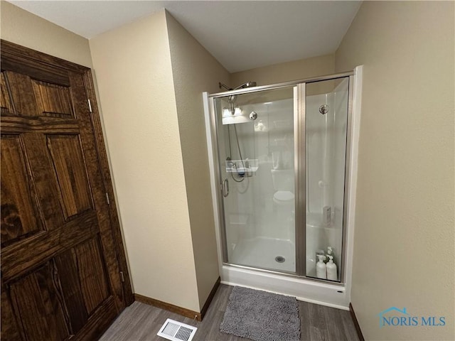 full bath with wood finished floors, baseboards, and a stall shower