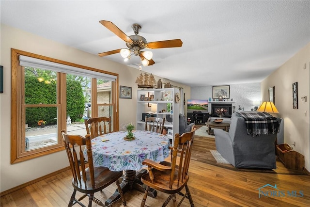 2659 Coveview Dr, Toledo, OH 43611 - dining space featuring wood finished floors, a lit fireplace, ceiling fan, and baseboards