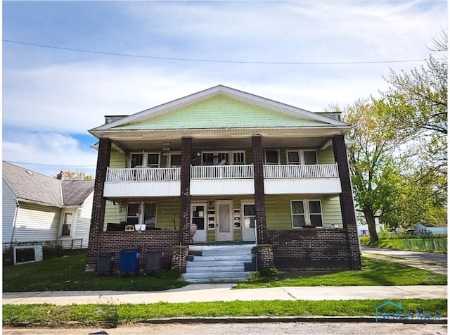 1202 Nevada St, Toledo, OH 43605 - view of front facade with covered porch, a balcony, brick siding, and a front lawn