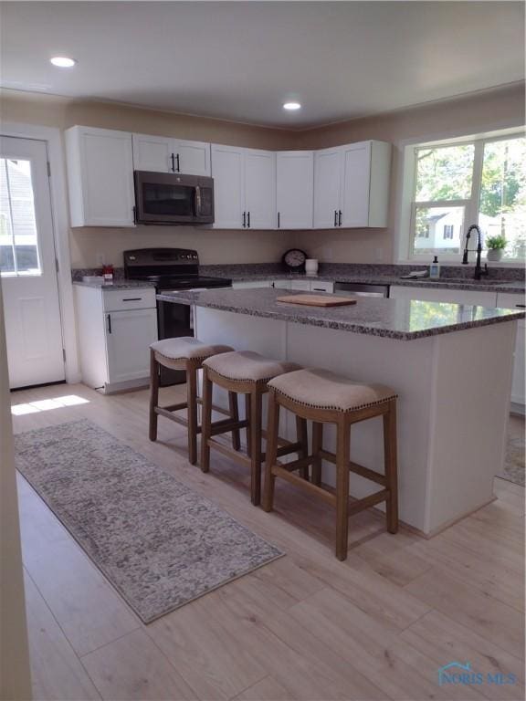 S832 County Road 20b, Archbold, OH 43555 - kitchen featuring electric range, a sink, a kitchen island, a breakfast bar area, and white cabinetry