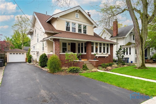 view of front of home with an outdoor structure, brick siding, a garage, a front lawn, and covered porch