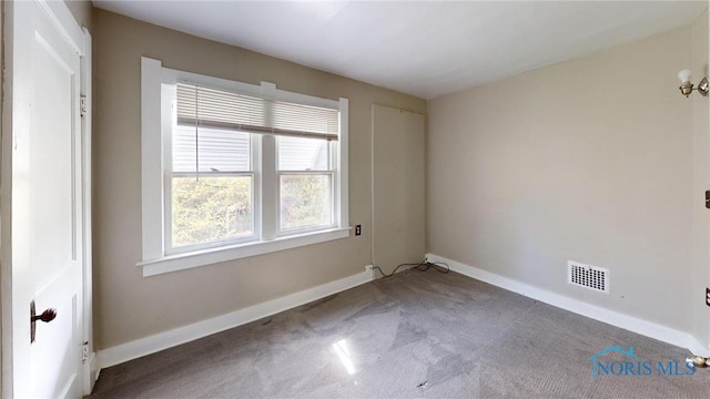 carpeted empty room featuring baseboards