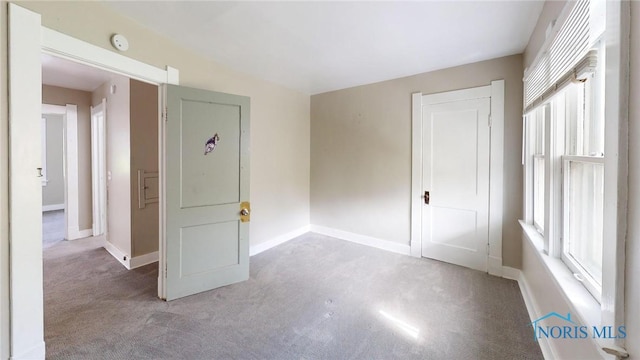 carpeted empty room with a smoke detector and baseboards