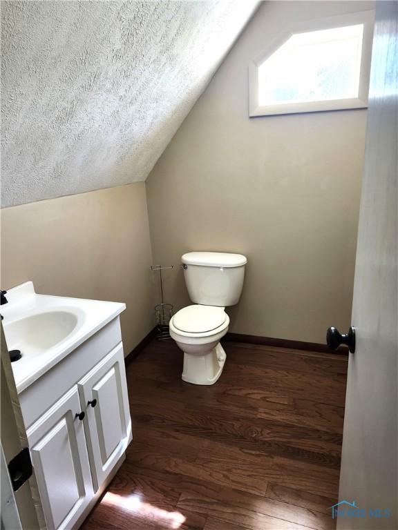 900 Leonard St, Fostoria, OH 44830 - bathroom featuring vaulted ceiling, toilet, vanity, a textured ceiling, and wood finished floors