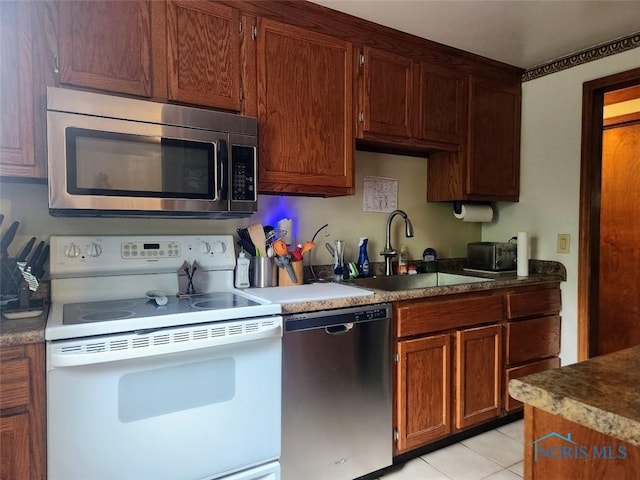 4405 Oldenburg Dr, Toledo, OH 43611 - kitchen with appliances with stainless steel finishes, a sink, light tile patterned flooring, and brown cabinets