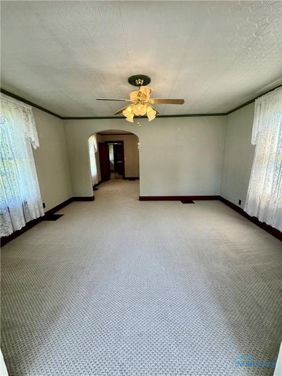 211 S Keyser St, Holgate, OH 43527 - unfurnished room with a ceiling fan, arched walkways, baseboards, and light carpet