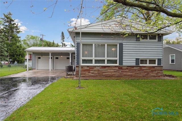 1639 Brookside Dr, Findlay, OH 45840 - view of front of house with an attached garage, central air condition unit, driveway, and stone siding