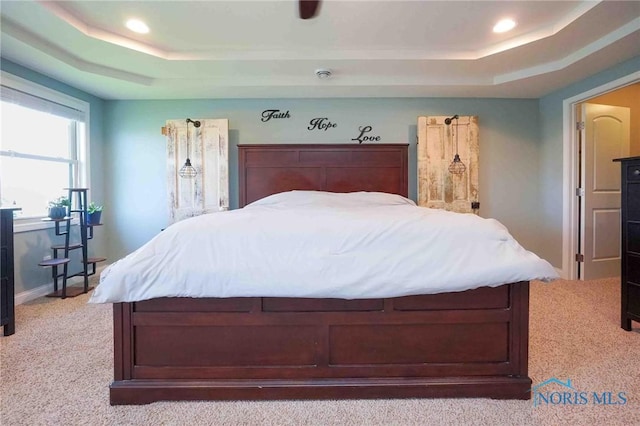bedroom featuring a raised ceiling, light carpet, recessed lighting, and baseboards
