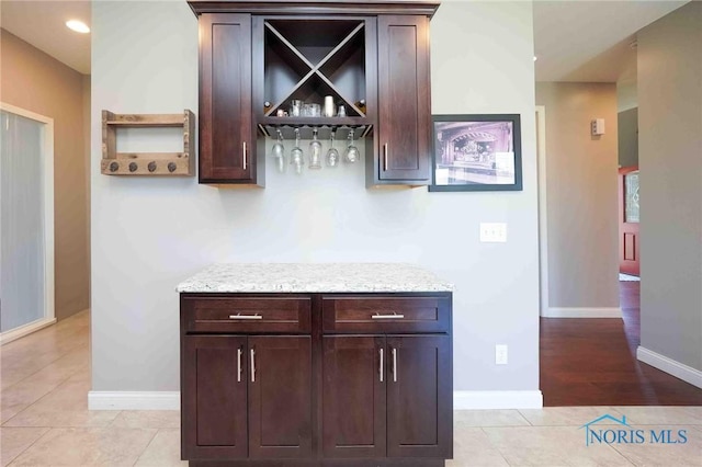 indoor dry bar featuring baseboards and light tile patterned floors