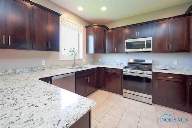 kitchen featuring appliances with stainless steel finishes, a sink, light tile patterned flooring, light stone countertops, and recessed lighting