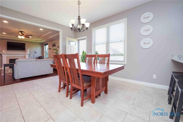 dining room with a tray ceiling, healthy amount of natural light, a chandelier, a fireplace, and recessed lighting