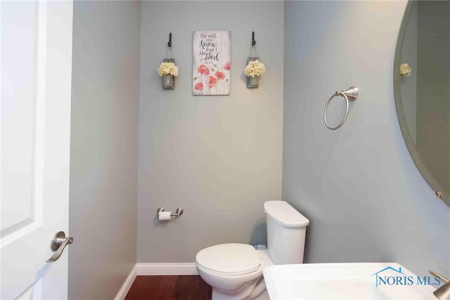 bathroom with toilet, baseboards, and wood finished floors