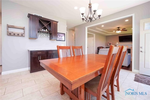 dining room with a tray ceiling, a chandelier, light tile patterned flooring, baseboards, and recessed lighting