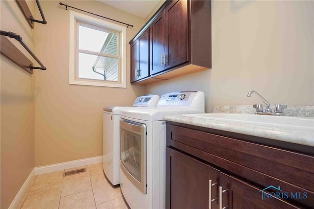 laundry room with cabinet space, washer and clothes dryer, baseboards, and light tile patterned flooring