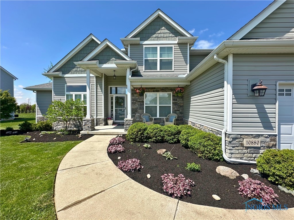 10880 Bay Trace Dr, Perrysburg, OH 43551 - view of front of home with stone siding, a front lawn, and a porch