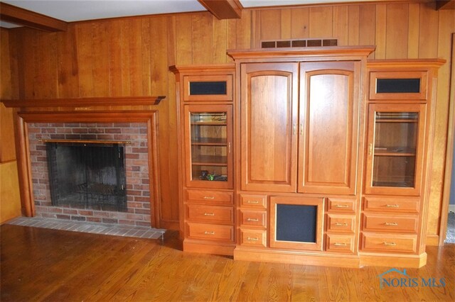 1527 S Ct, Findlay, OH 45840 - unfurnished living room featuring wood walls, beamed ceiling, wood finished floors, and a fireplace