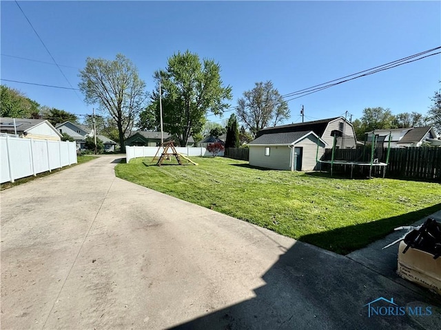 view of yard with a trampoline, an outbuilding, and a playground