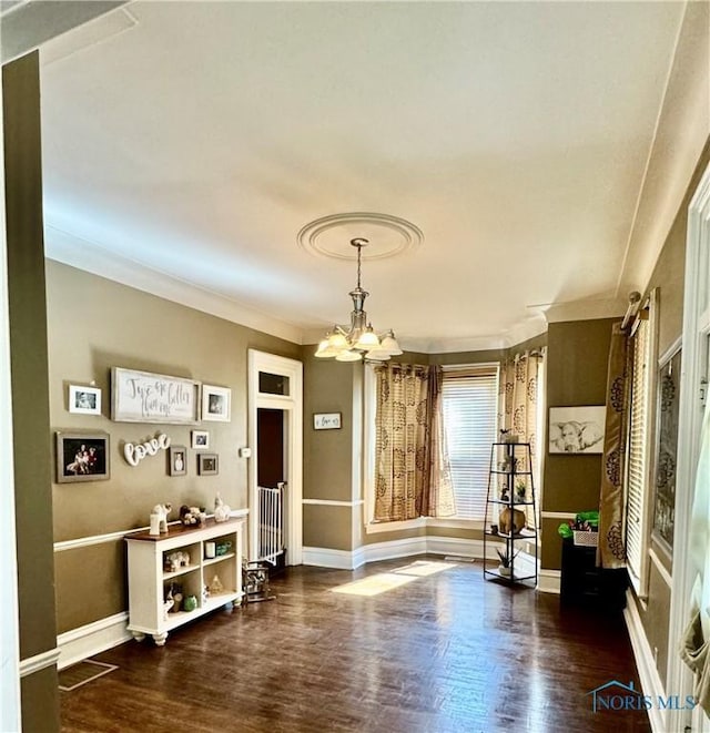 dining area featuring a chandelier, wood finished floors, crown molding, and baseboards