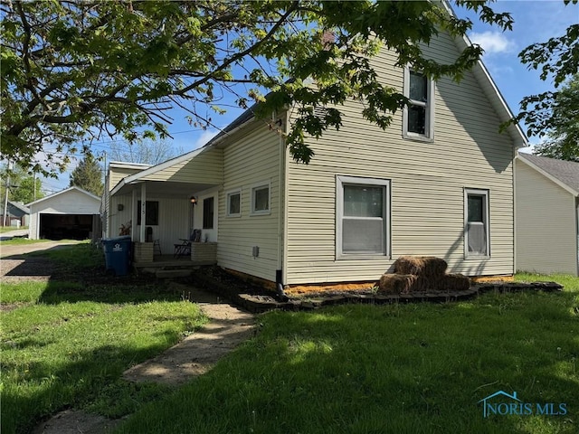 215 E Bryan St, Bryan, OH 43506 - view of home's exterior featuring a yard, covered porch, and a detached garage