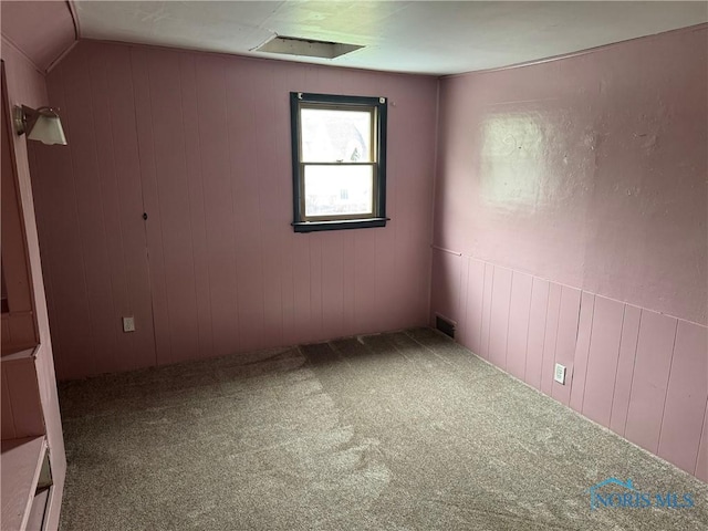 215 E Bryan St, Bryan, OH 43506 - carpeted empty room featuring vaulted ceiling and wooden walls