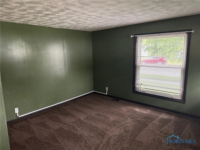 215 E Bryan St, Bryan, OH 43506 - unfurnished room featuring a textured ceiling, dark colored carpet, and baseboards