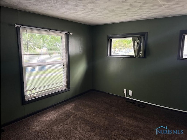 215 E Bryan St, Bryan, OH 43506 - spare room featuring a textured ceiling, dark carpet, and baseboards