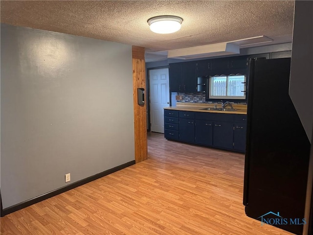 215 E Bryan St, Bryan, OH 43506 - kitchen featuring a textured ceiling, a sink, light wood finished floors, light countertops, and blue cabinets