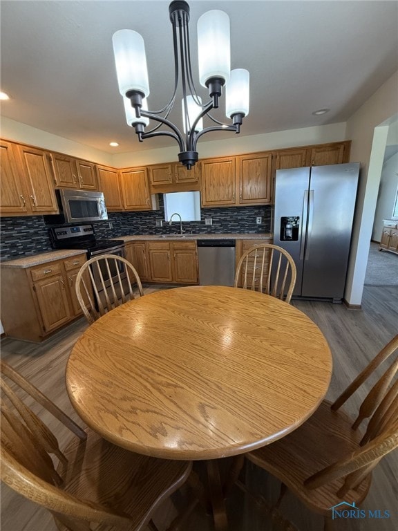 512 Fugate Dr, Defiance, OH 43512 - kitchen with appliances with stainless steel finishes, light wood-style flooring, a chandelier, a sink, and tasteful backsplash