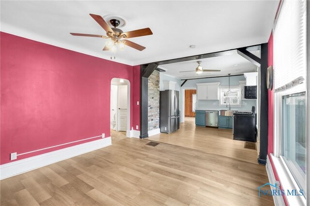308 Crittenden Ave, Toledo, OH 43609 - unfurnished living room with a ceiling fan, baseboards, arched walkways, light wood-type flooring, and a sink