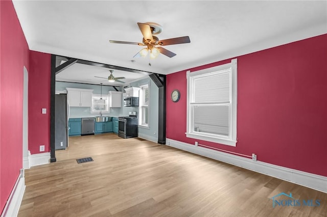 308 Crittenden Ave, Toledo, OH 43609 - unfurnished living room featuring a ceiling fan, baseboards, light wood finished floors, and a sink