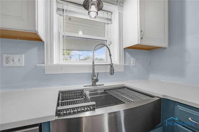308 Crittenden Ave, Toledo, OH 43609 - kitchen view of light countertops, blue cabinetry, a sink, and white cabinetry