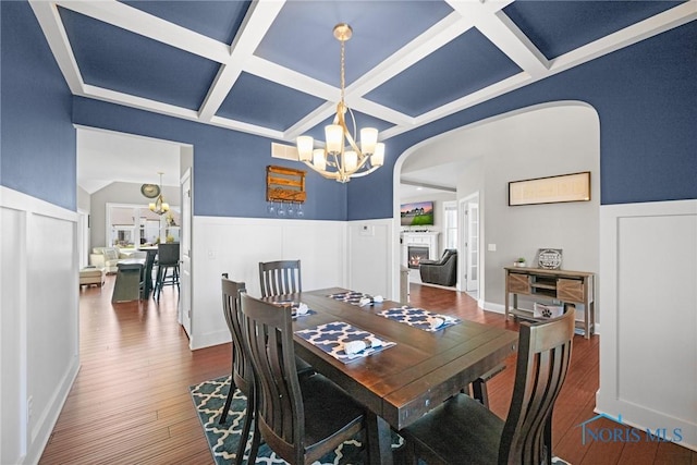 9575 Newbury Ln, Whitehouse, OH 43571 - dining room featuring coffered ceiling, a chandelier, arched walkways, wood finished floors, and a lit fireplace