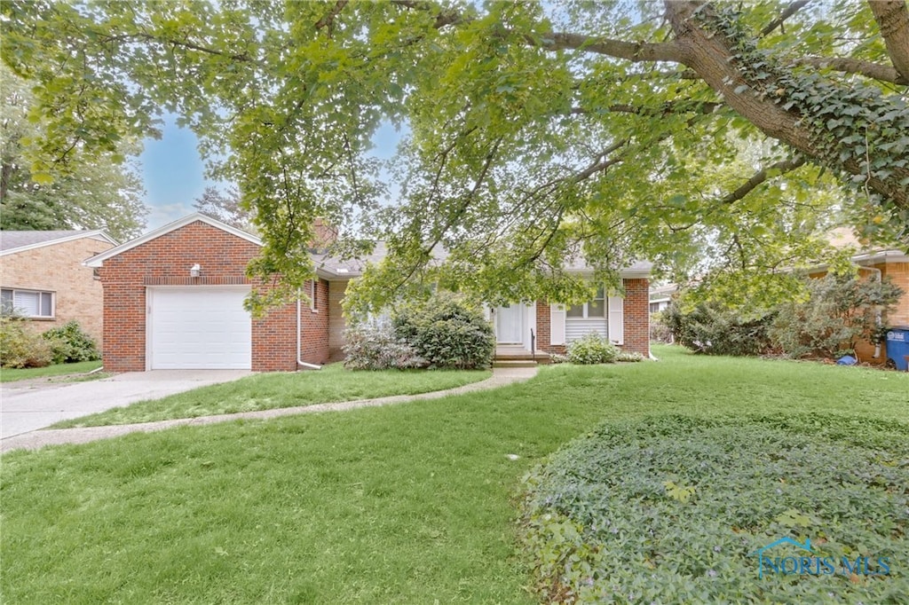 2633 Evergreen Rd, Toledo, OH 43606 - view of property hidden behind natural elements featuring brick siding, a front yard, a garage, and driveway
