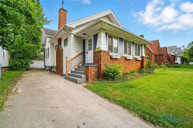 4315 Eastway St, Toledo, OH 43612 - view of front of house with a chimney, a front lawn, brick siding, and an outdoor structure