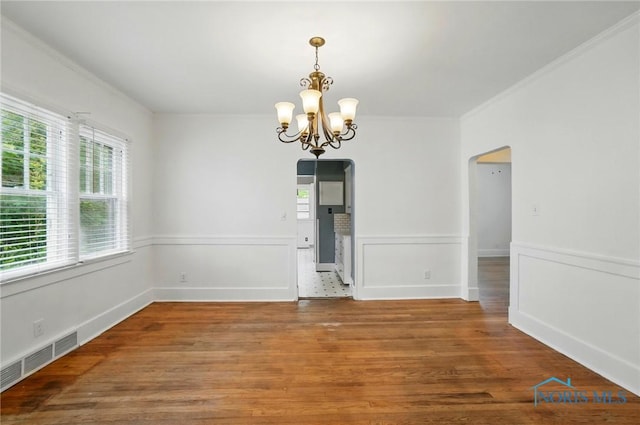 4315 Eastway St, Toledo, OH 43612 - unfurnished dining area featuring arched walkways, a chandelier, ornamental molding, and wood finished floors