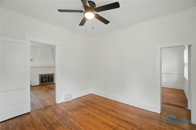 4315 Eastway St, Toledo, OH 43612 - empty room featuring a ceiling fan, ornamental molding, wood finished floors, a brick fireplace, and baseboards