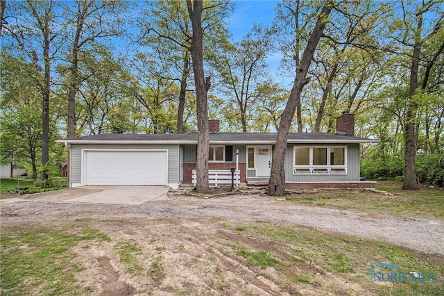 ranch-style house with a chimney, concrete driveway, a garage, and brick siding